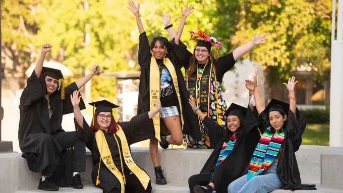 Graduates raising their hands on campus together
