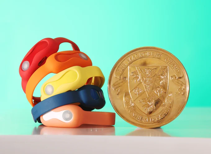 A stack of DnaNudge wristbands next to the MacRobert Award gold medal