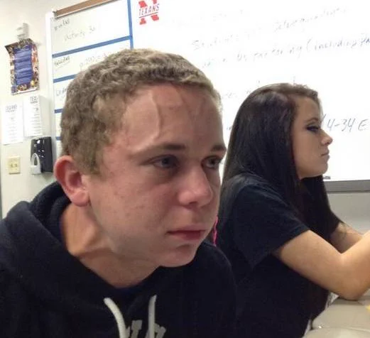 A teenager sitting in class, with bulging veins, looking like he is going to burst any second