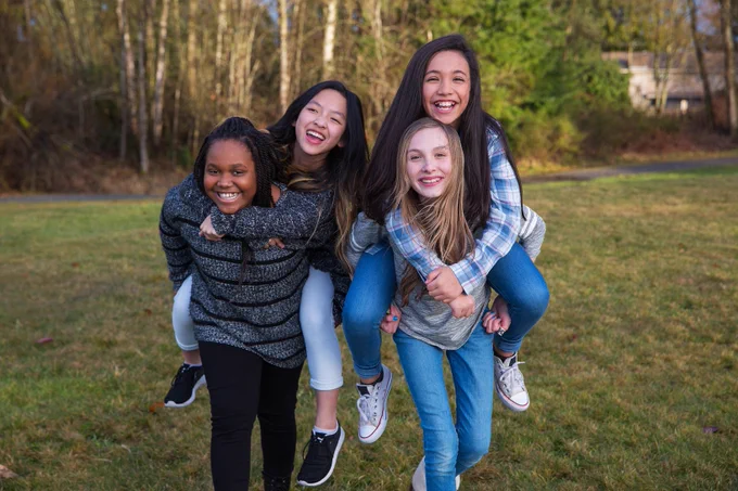 Group of four kids playing and giving piggyback rides. Courtesy of Adobe Stock. 