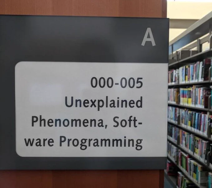 Library end sign says unexplained phenomena and software programming books are contained in that aisle