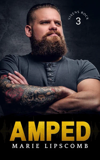 Large man with tattooed arms crossed infront of his chest. He has a big brown beard and is looking off into the distance. Amped by Marie Lipscomb. 