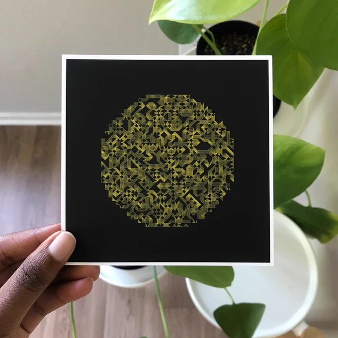 A picture of me holding a print in front of a backdrop of plants. The print is interwoven golden lines on a black background. 