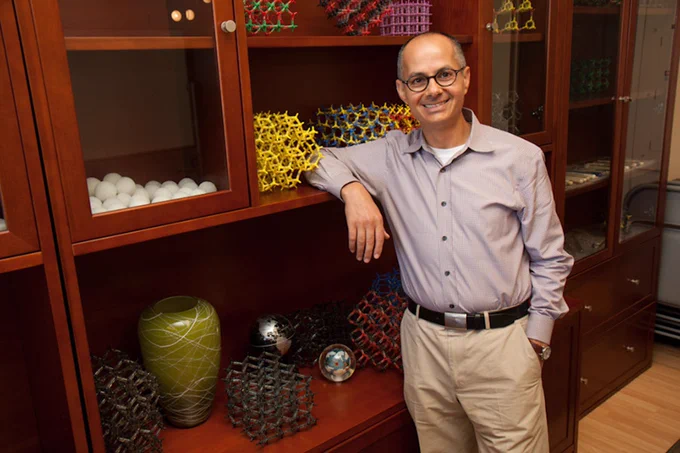 Omar Yaghi standing in front of a bookshelf and smiling into the camera. 