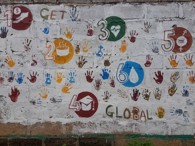 wall painted with SDG logos and student handprints 