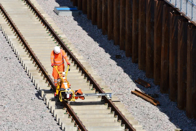 An engineer checks the gauge of the new track that has been installed.