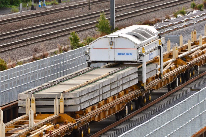 A close up of sleepers stacked up on the track laying train.