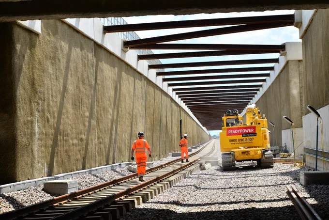 Engineers walk along the newly installed track inside one of the entry and exit ramps to the tunnel.