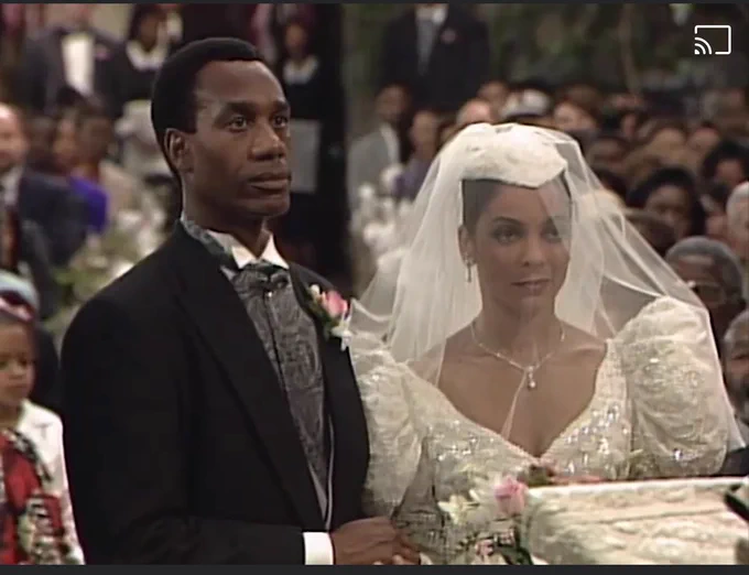 Poppa Pope and Whitley Gilbert at the alter of the wedding that did not happen. Many many years ago. Poppa Pope in a tux and Whitley in a weeding gown seen from the waist up.