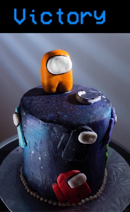 “Among Us” cake in galaxy dark blue sparkle, decorated with crewmates, with orange crewmate topper and “Victory” caption above 