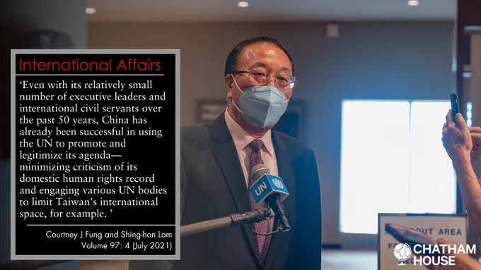 China Permanent Representative to the UN Ambassador Zhang Jun talks to the press in a large room while wearing a blue face mask. 