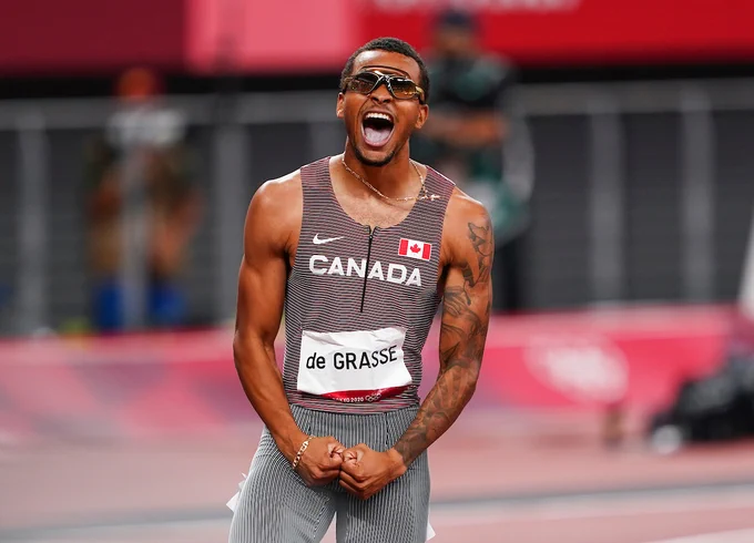 Andre De Grasse celebrates after winning Olympic gold. Standing and yelling.