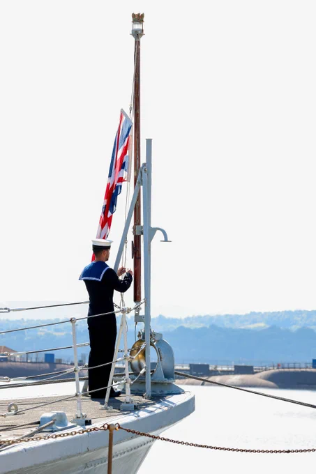 A sailor lowers the Union Jack on the forecastle of HMS Blyth