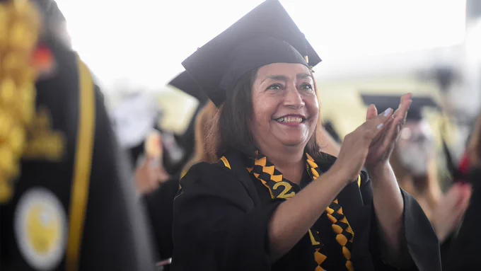 Grad in cap and gown claps