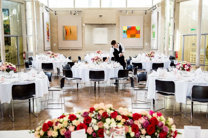 Dining hall in the Dome with tables set out for a wedding. Art is hung on the walls.