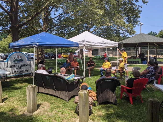 Neighbors seated in a circle talking in a park.