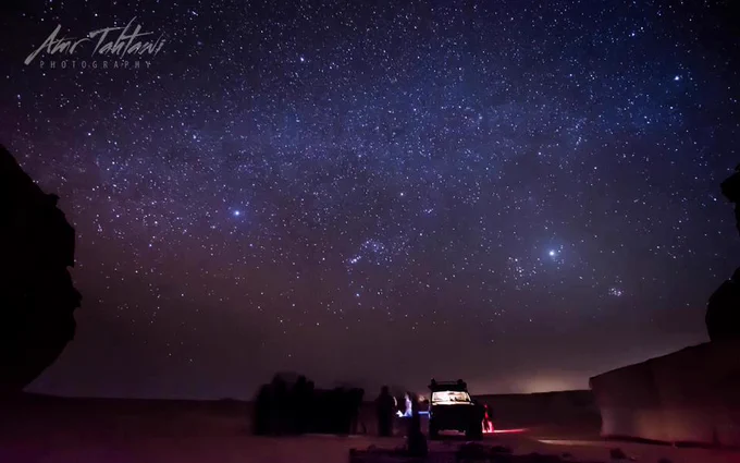 This is a photo in the desert of the Valley of whales in Egypt featuring a sky full of stars. 