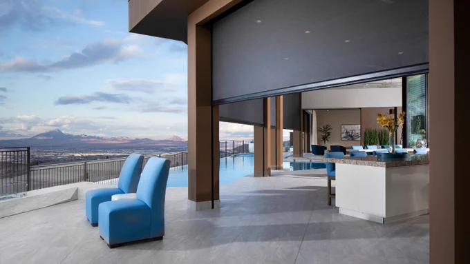 A photo of an outdoor living space of a home with the landscape view. Phantom Screens are installed between the walls and they partially cover the swimming pool.