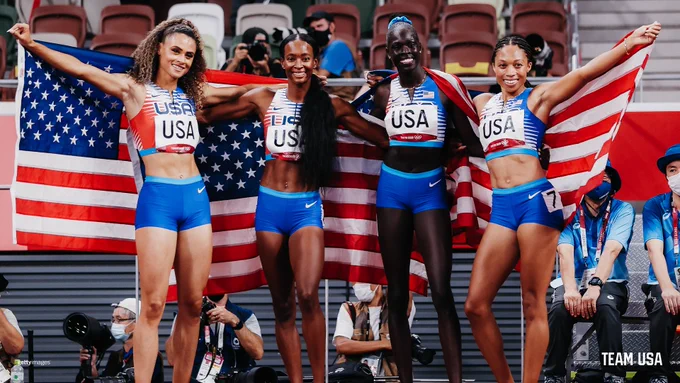 Photo of the U.S Women's 4x400m relay holding the U.S. flag after winning gold. 