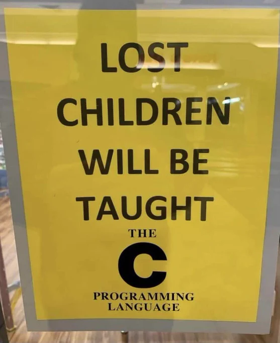 Sign, black text on yellow background, reading "lost children will be taught the c programming language"