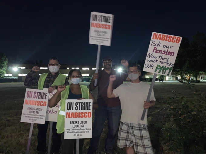 Nabisco workers on strike. Holding picket signs. One reads Nabisco took our penson now they want to take our pay