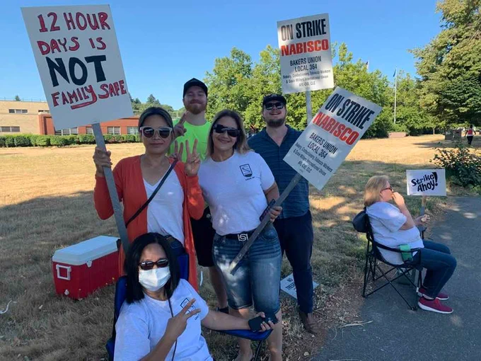 More nabisco workers on strike holding picket signs. One reads 12 hour days are not family safe.