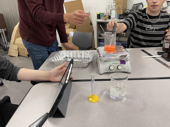 Students melting candy on a hot plate and measuring the temperature