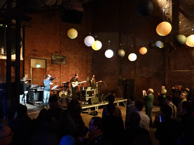  A band plays on a stage in a venue with a BSL interpreter