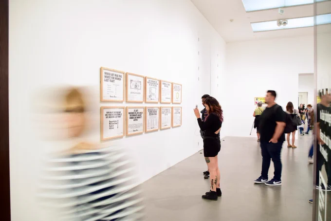 People looking at artworks on the wall of a gallery.