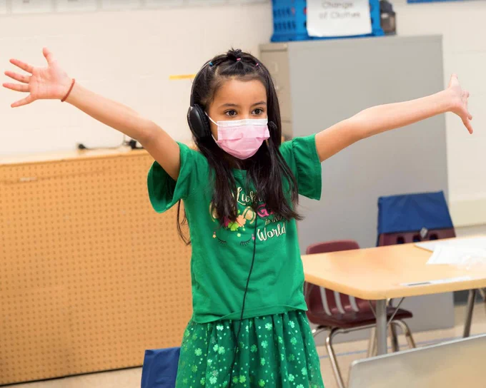 Student in all green and arms raised. 