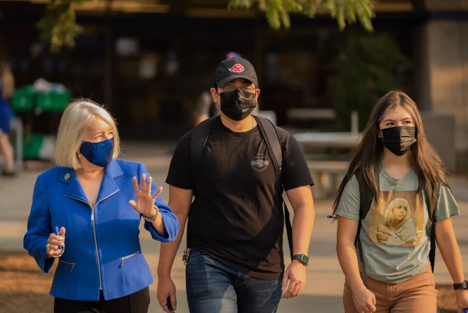 Three people wearing face masks walking outside. 