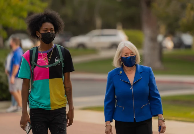 Two women walking outside and wearing face masks. 