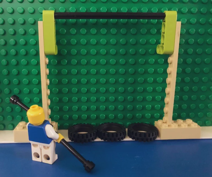 Lego mini figure holding what appears to be a circus balance pole. Lego technix and other pieces are configured to be a tightrope.