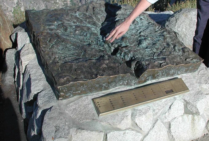 A 3 dimensional exhibit map depicts Yosemite Valley. Someone's hand is touching an area in the valley.
