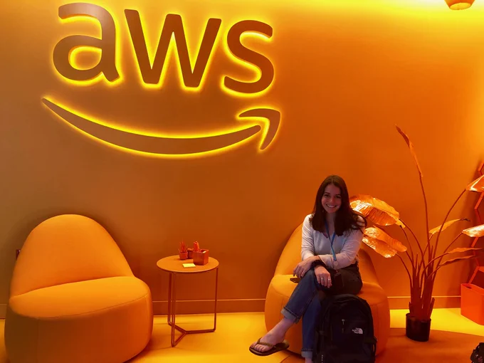 student sits in orange chair in front of orange AWS Amazon logo