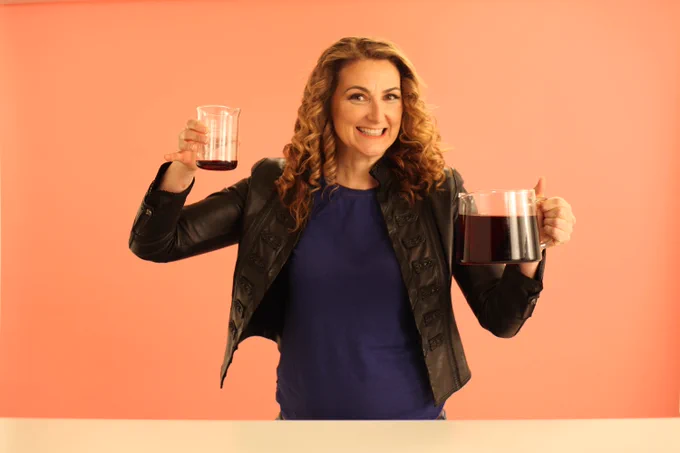 Dr. Jen Gunter holding two beakers filled with coffee.