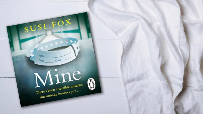 The audiobook cover of Mine on a white wood background next to a soft, white blanket