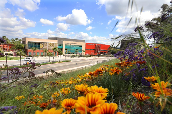 View of Cal State LA University-Student Union building from the hill across Paseo Rancho Castilla near bright colorful orange and purple flowers