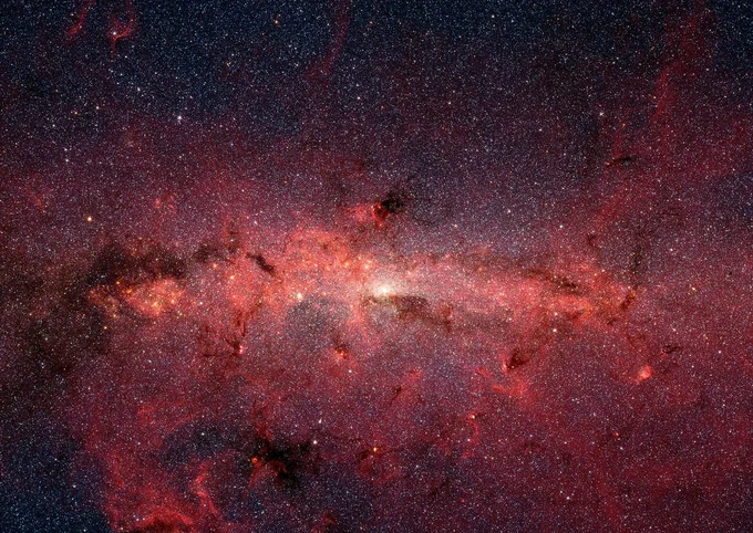 The center of our galaxy is crowded with reddish dust and millions of stars in this infrared image from NASA's Spitzer Space Telescope