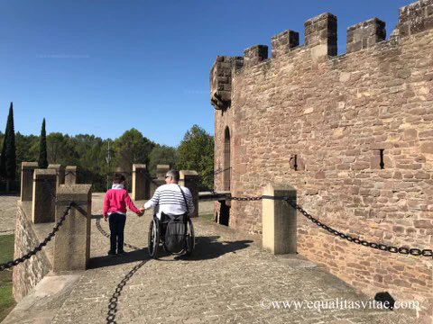 Kity(usuario de silla de ruedas) entrando de la mano de su hijo en el Castillo por una rampa de piedra