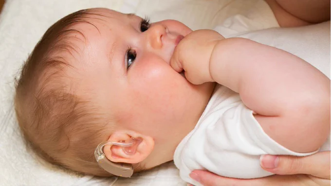 Baby boy with hearing aid.