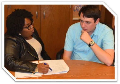 An African-american woman asks a man questions as part of a survey. The man looks inquisitively as he responds to her questions. 