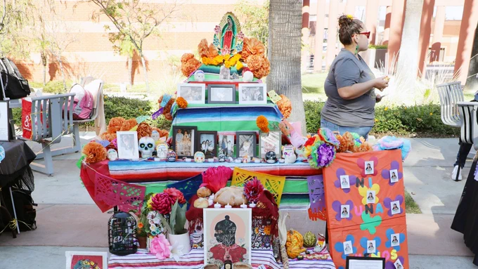 The photo is of a colorful alter with photos of deceased loved ones and traditional Dia de los Muertos items on it.