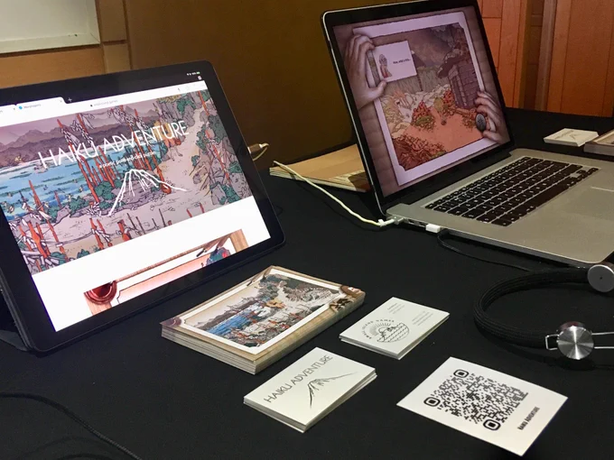 Photograph of a desk with computers displaying the game Haiku Adventure. 