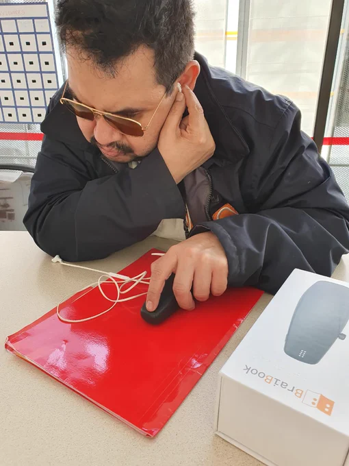 Señor leyendo en braille y escuchando la lectura con BraiBook