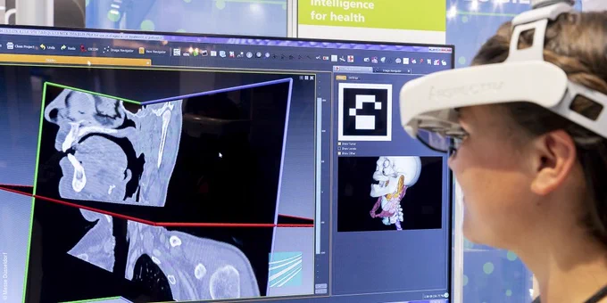 Woman wearing virtual reality glasses and looking at a display; Copyright: Messe Düsseldorf