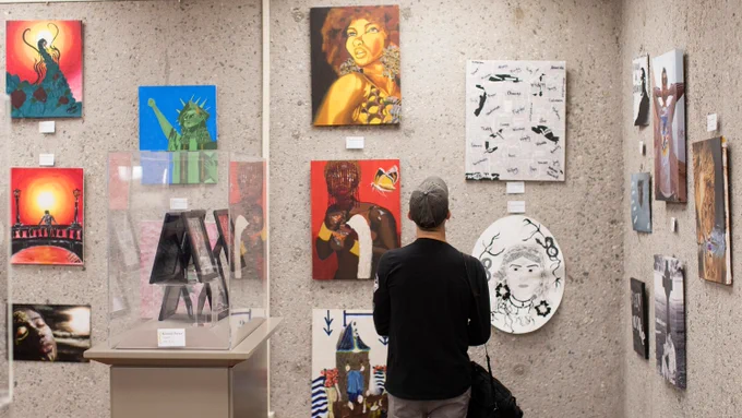 1 person standing looking at a wall with art frames. 