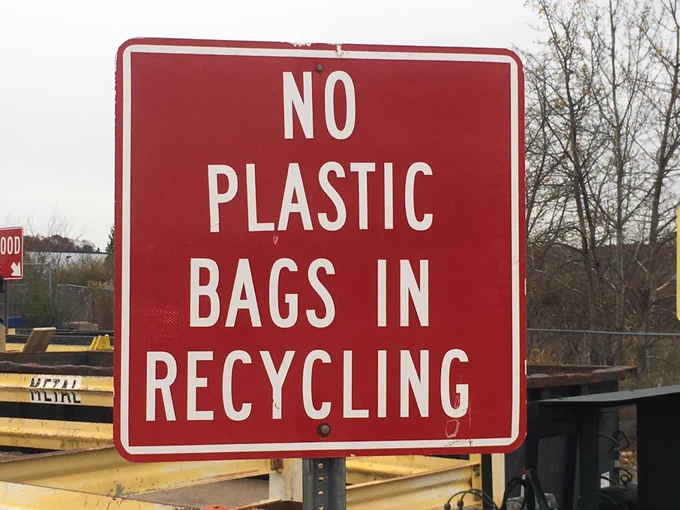 Image of a red sign stating "No plastic bags in recycling".