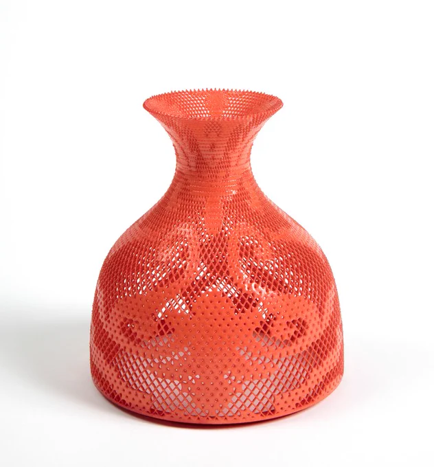 This is a vessel with an elegant form. The vessel is orange-pink. It has designs that look like rococo swirls.