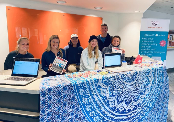 group of 6 students standing behind an informational booth for EquatIO.  Laptops on counter, Equatio promotional flyers, and candy.  
